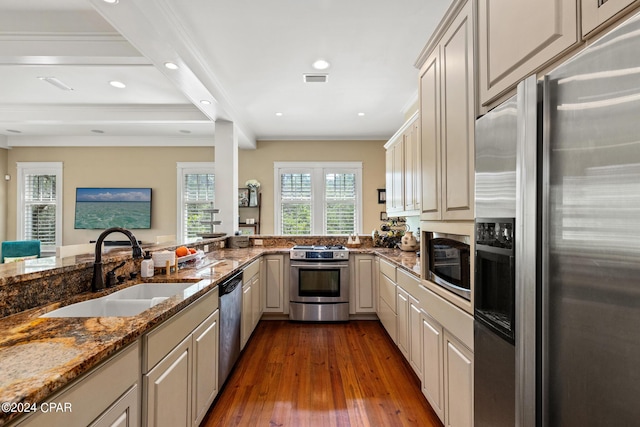 kitchen featuring stainless steel appliances, sink, kitchen peninsula, dark stone counters, and beam ceiling