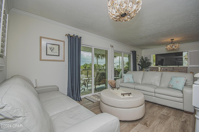 living room featuring light hardwood / wood-style flooring, a chandelier, a textured ceiling, and ornamental molding