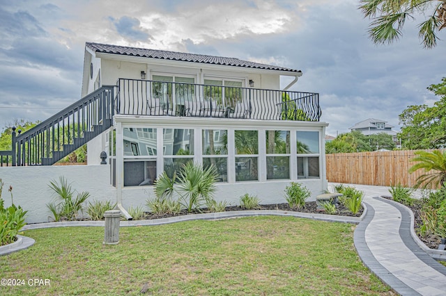 rear view of property featuring a yard and a balcony