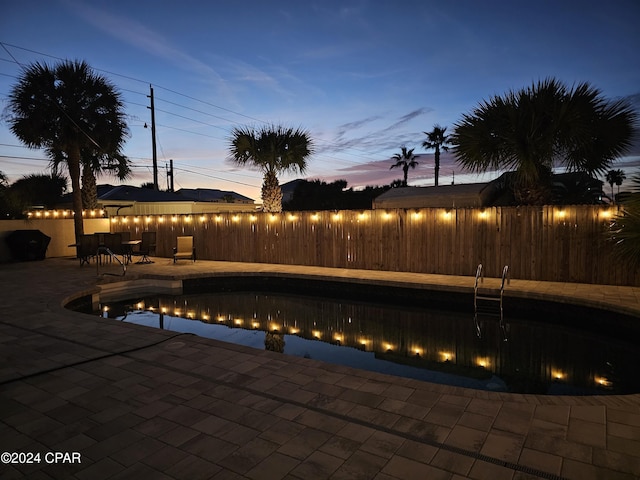 pool at dusk with a patio area