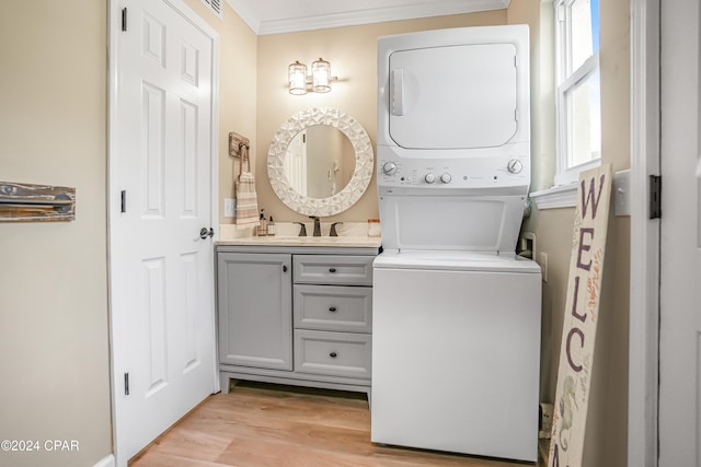 bathroom featuring vanity, wood-type flooring, crown molding, and stacked washer and clothes dryer