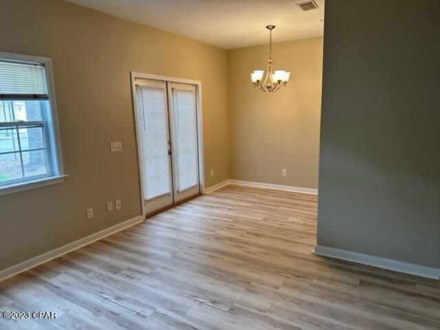 empty room featuring an inviting chandelier, wood-type flooring, and french doors