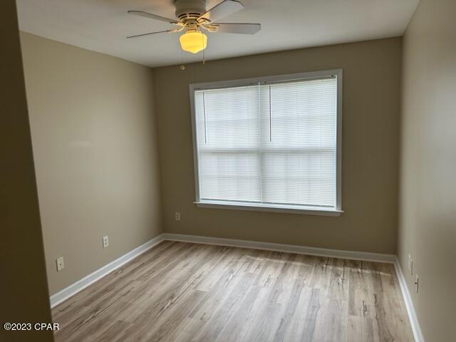 empty room with ceiling fan and light hardwood / wood-style flooring