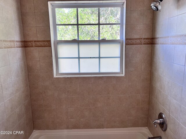 bathroom featuring a wealth of natural light and tiled shower / bath combo