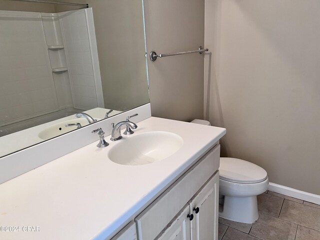 bathroom with tile patterned floors, a shower, vanity, and toilet