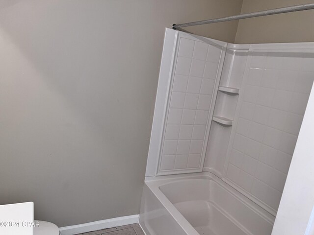 bathroom with tile patterned flooring, tiled shower / bath combo, and toilet