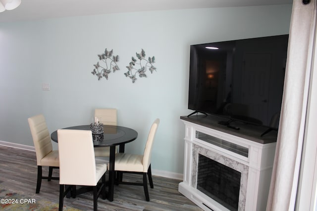 dining area featuring a premium fireplace, baseboards, and wood finished floors