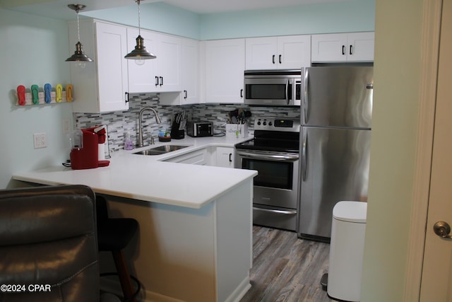 kitchen featuring a breakfast bar, backsplash, appliances with stainless steel finishes, a sink, and a peninsula