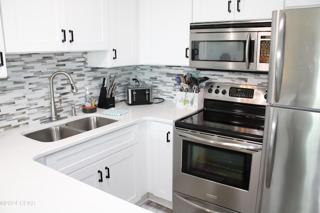 kitchen with backsplash, stainless steel appliances, a sink, and light countertops