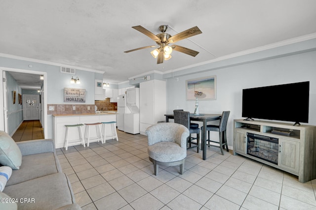 tiled living room with ceiling fan and crown molding