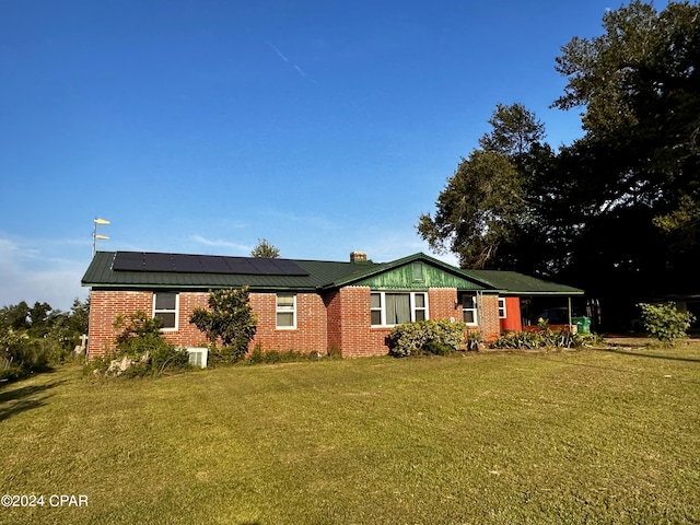 single story home featuring central air condition unit, solar panels, and a front yard