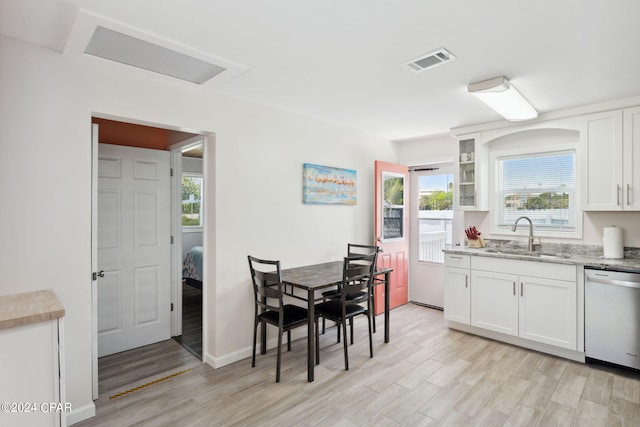 kitchen featuring white cabinets, light hardwood / wood-style floors, light stone counters, dishwasher, and sink