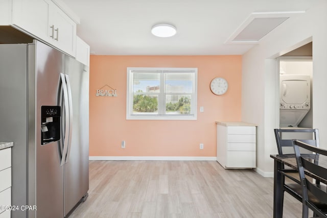 kitchen with white cabinets, stainless steel fridge with ice dispenser, light hardwood / wood-style floors, and stacked washing maching and dryer