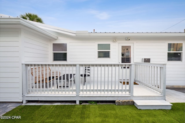 back of house featuring a wooden deck and a lawn