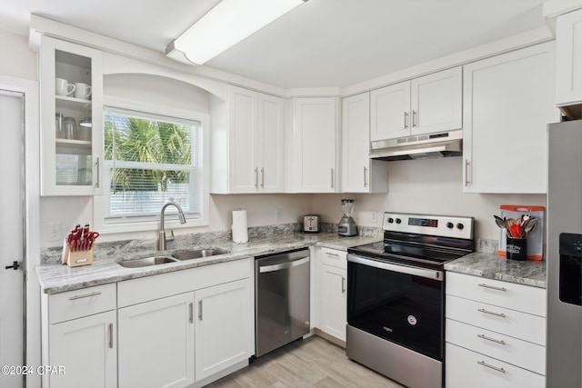 kitchen featuring sink, appliances with stainless steel finishes, light stone counters, light hardwood / wood-style floors, and white cabinets