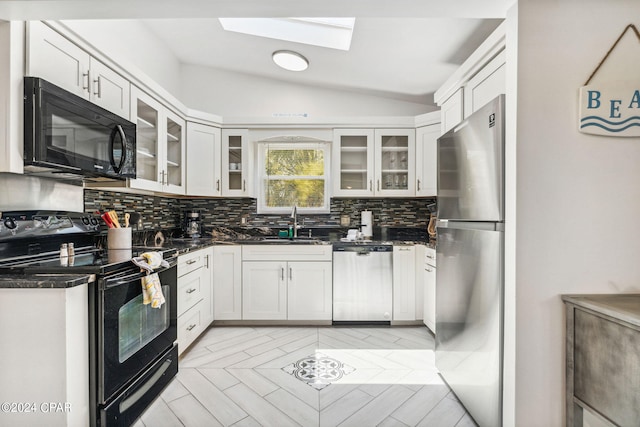 kitchen featuring tasteful backsplash, black appliances, white cabinetry, and vaulted ceiling with skylight