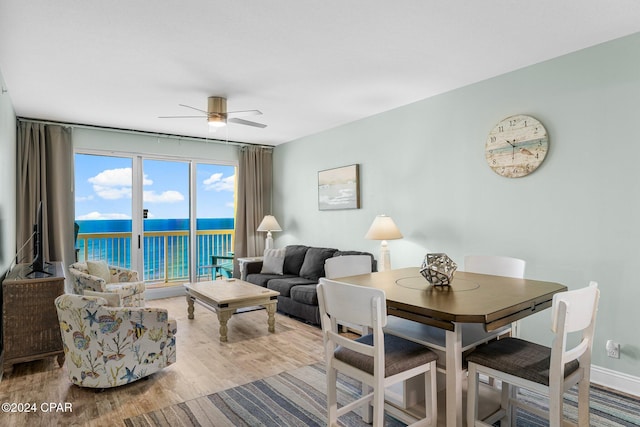 living room featuring ceiling fan, a water view, and light wood-type flooring