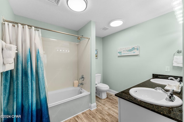 full bathroom with shower / bath combo with shower curtain, hardwood / wood-style floors, vanity, and toilet