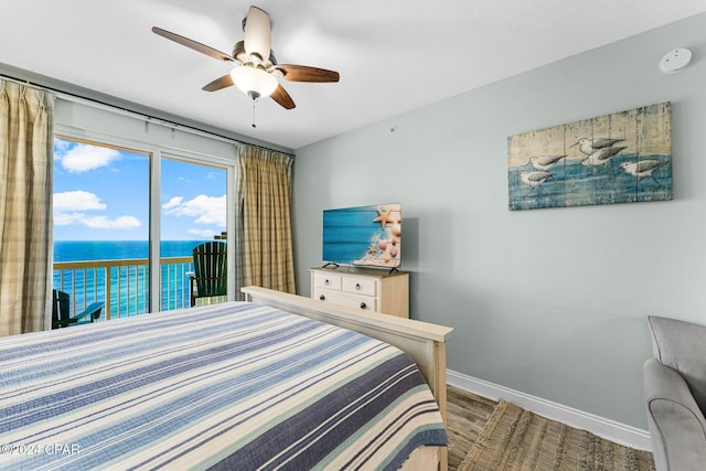 bedroom with access to exterior, ceiling fan, a water view, and hardwood / wood-style flooring