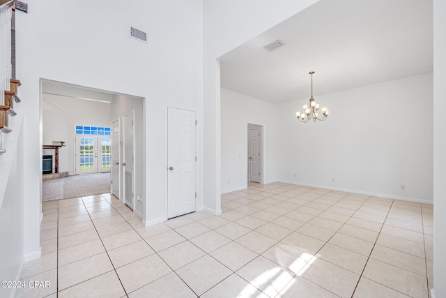 empty room with a notable chandelier and light tile patterned floors