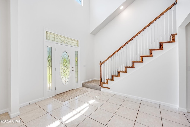 entryway featuring a towering ceiling, a healthy amount of sunlight, and light tile patterned floors