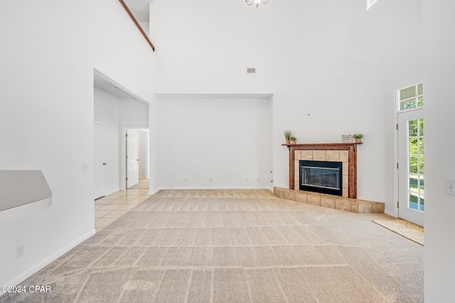 unfurnished living room featuring light carpet, a high ceiling, and a tile fireplace