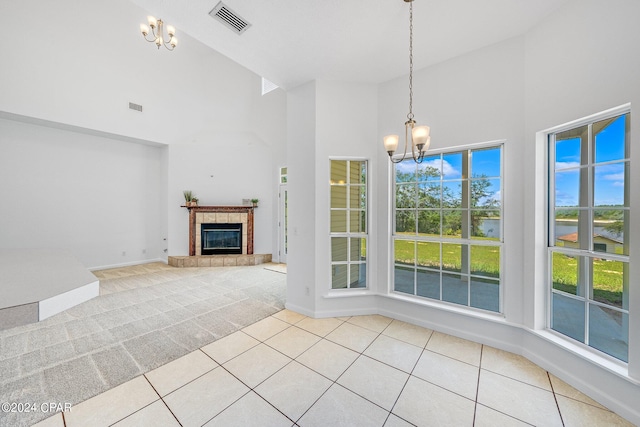 unfurnished living room featuring light colored carpet, a fireplace, an inviting chandelier, and a high ceiling