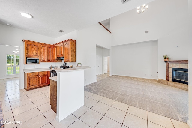 kitchen with a notable chandelier, light colored carpet, electric stove, and a fireplace