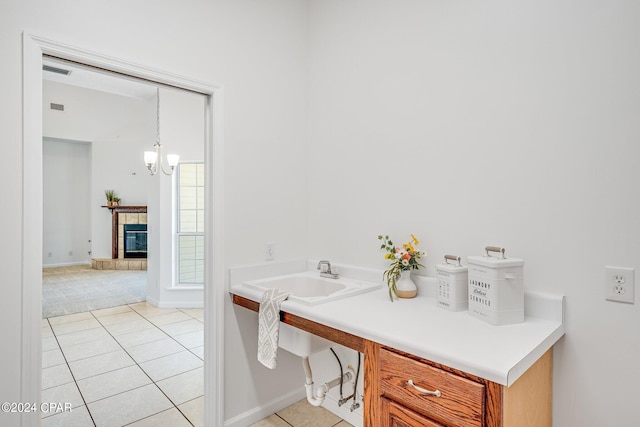 bathroom featuring tile patterned floors, an inviting chandelier, sink, and a tiled fireplace