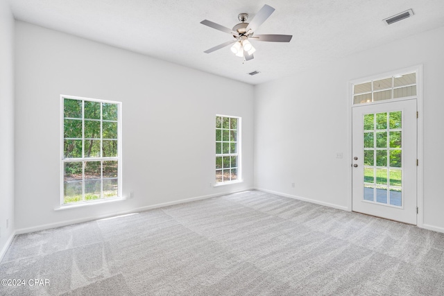 spare room with ceiling fan, plenty of natural light, and carpet floors