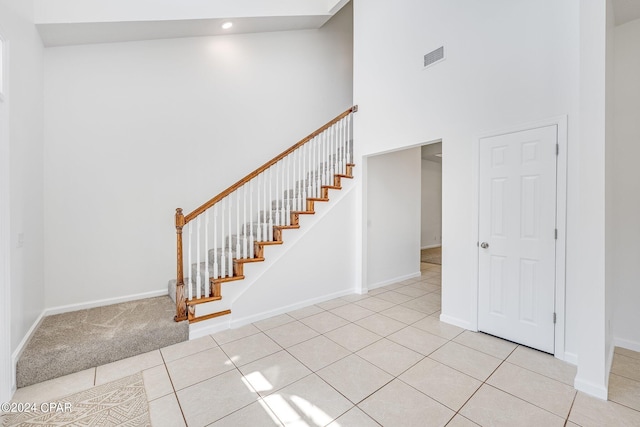 staircase featuring tile patterned flooring and high vaulted ceiling