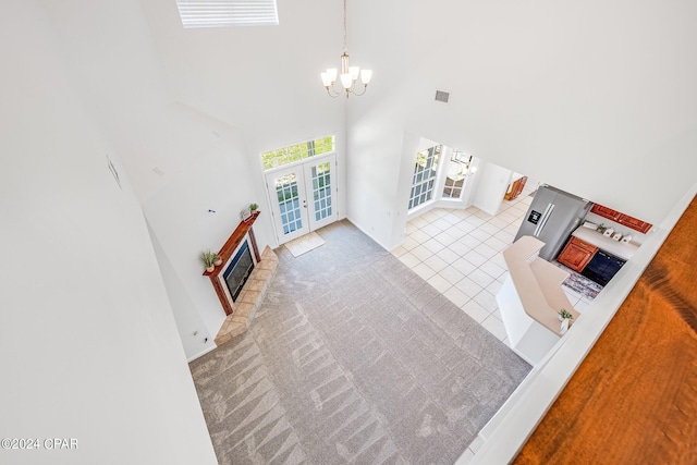 living room with french doors, a towering ceiling, a notable chandelier, and light colored carpet