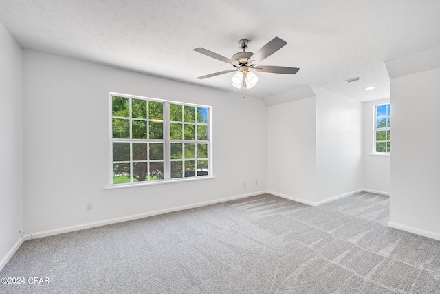 spare room featuring ceiling fan, carpet floors, and a healthy amount of sunlight