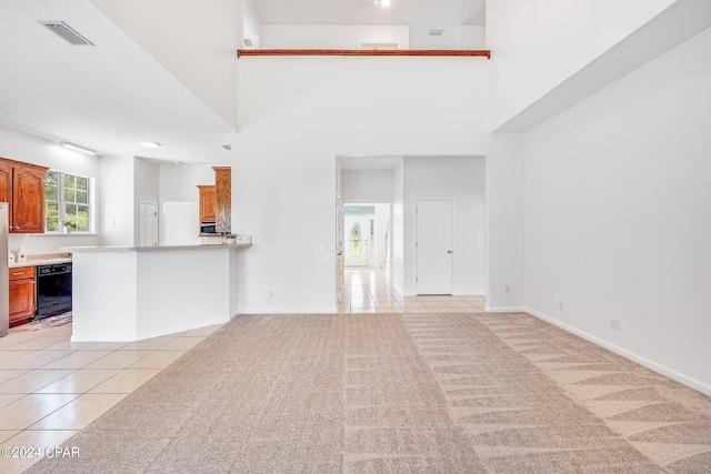 unfurnished living room with a towering ceiling and light carpet