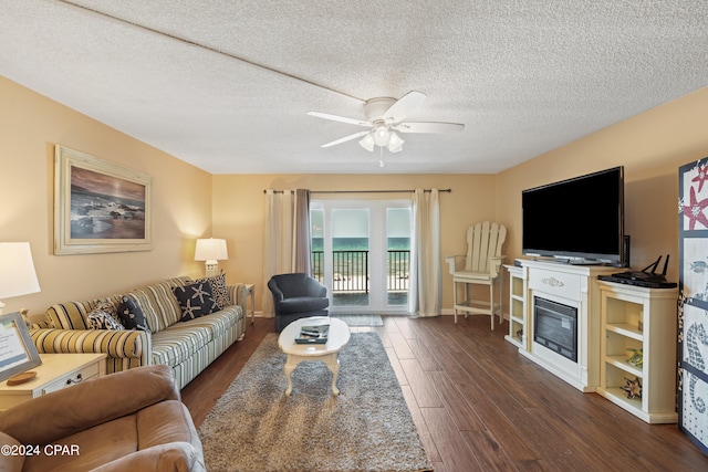 living room featuring a textured ceiling, ceiling fan, and dark wood-type flooring