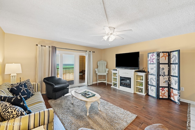 living room featuring dark hardwood / wood-style floors, ceiling fan, and a textured ceiling