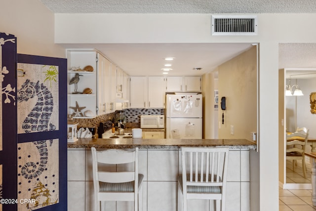 kitchen featuring light tile patterned floors, tasteful backsplash, white cabinets, white appliances, and kitchen peninsula