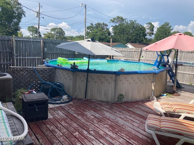 wooden terrace featuring central AC unit and a fenced in pool