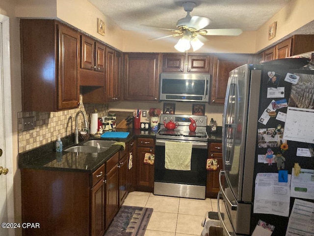 kitchen featuring stainless steel appliances, sink, backsplash, light tile patterned floors, and ceiling fan