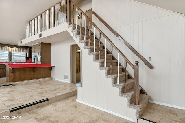 stairs with a towering ceiling and light tile patterned floors