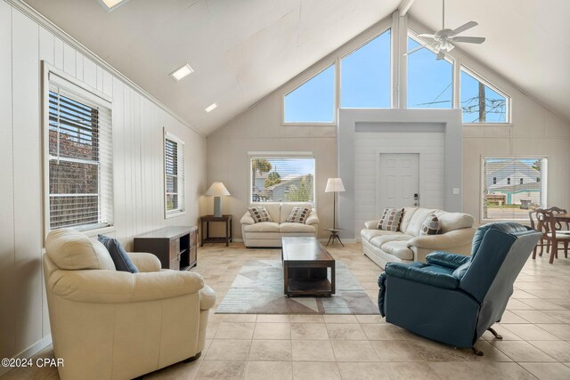 tiled living room with ceiling fan and high vaulted ceiling