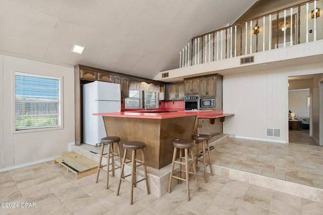 kitchen featuring vaulted ceiling, dark brown cabinetry, appliances with stainless steel finishes, and light tile patterned floors