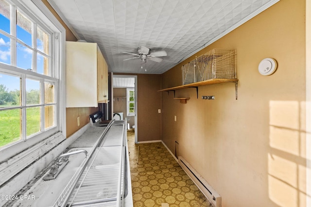 kitchen with ornamental molding, a baseboard heating unit, ceiling fan, and a healthy amount of sunlight