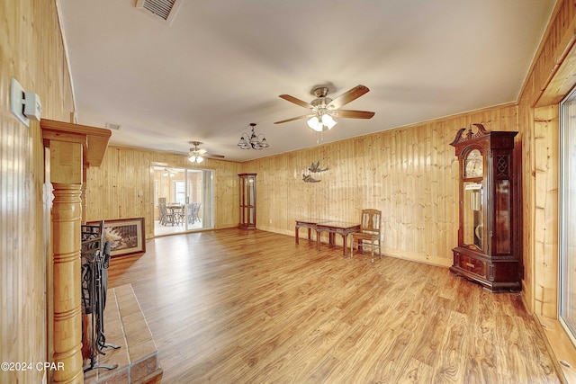 unfurnished living room featuring wood walls, ceiling fan, and light hardwood / wood-style floors