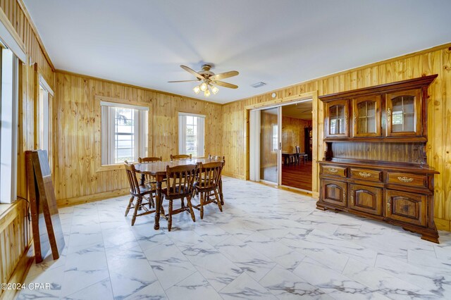 tiled dining space featuring wooden walls and ceiling fan