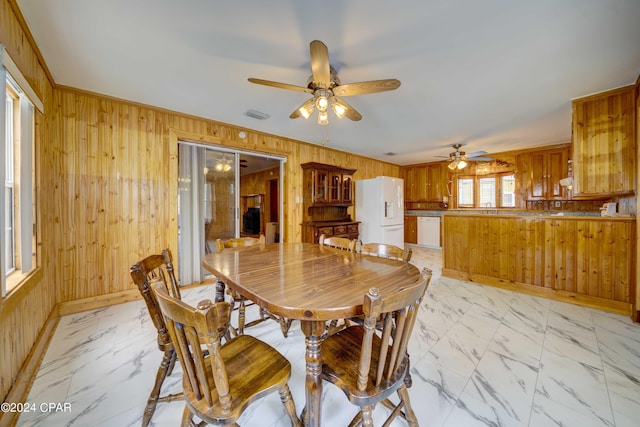 tiled dining room with ceiling fan and wooden walls