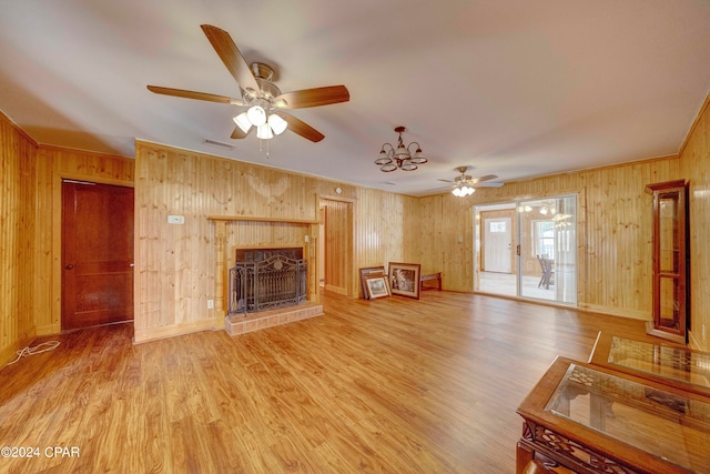 unfurnished living room with ceiling fan, light wood-type flooring, wood walls, and a fireplace