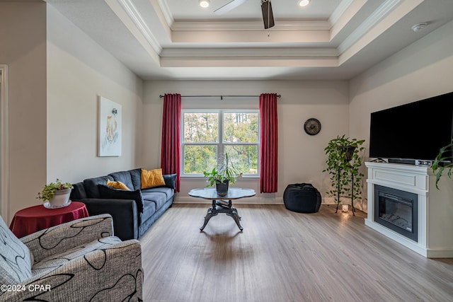 living room featuring ceiling fan, a tray ceiling, and light hardwood / wood-style floors