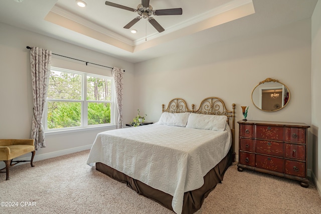 carpeted bedroom featuring ceiling fan, a tray ceiling, and ornamental molding