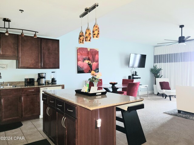 kitchen featuring sink, ceiling fan, a kitchen breakfast bar, a kitchen island, and decorative light fixtures